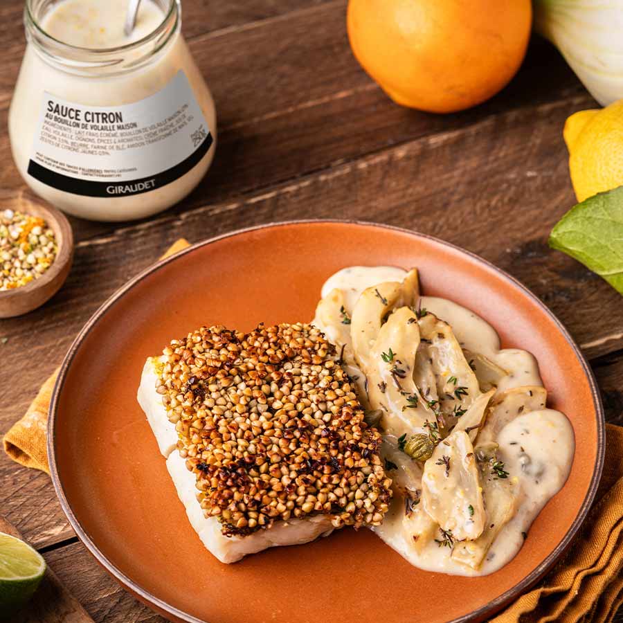 Une assiette comprenant un filet de cabillaud en croûte de sarrasin, un fenouil braisé à la poêle nappé d'une sauce citron