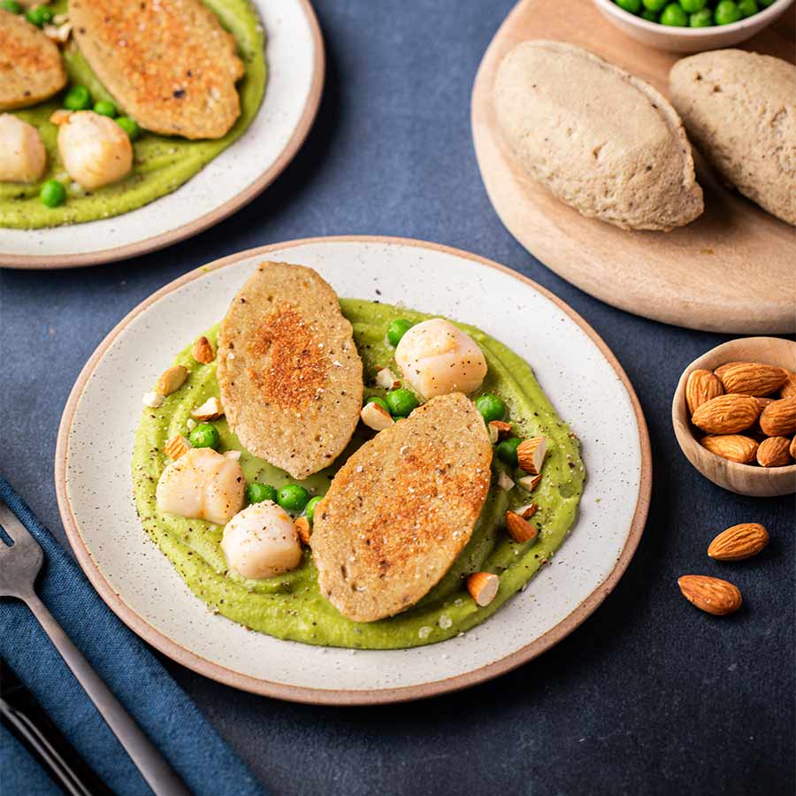 Une quenelle tranchée en deux, sur son lit onctueux de crémeux de fèves. Autour, des noix de Saint-Jacques , des petits pois et des amandes concassées.
